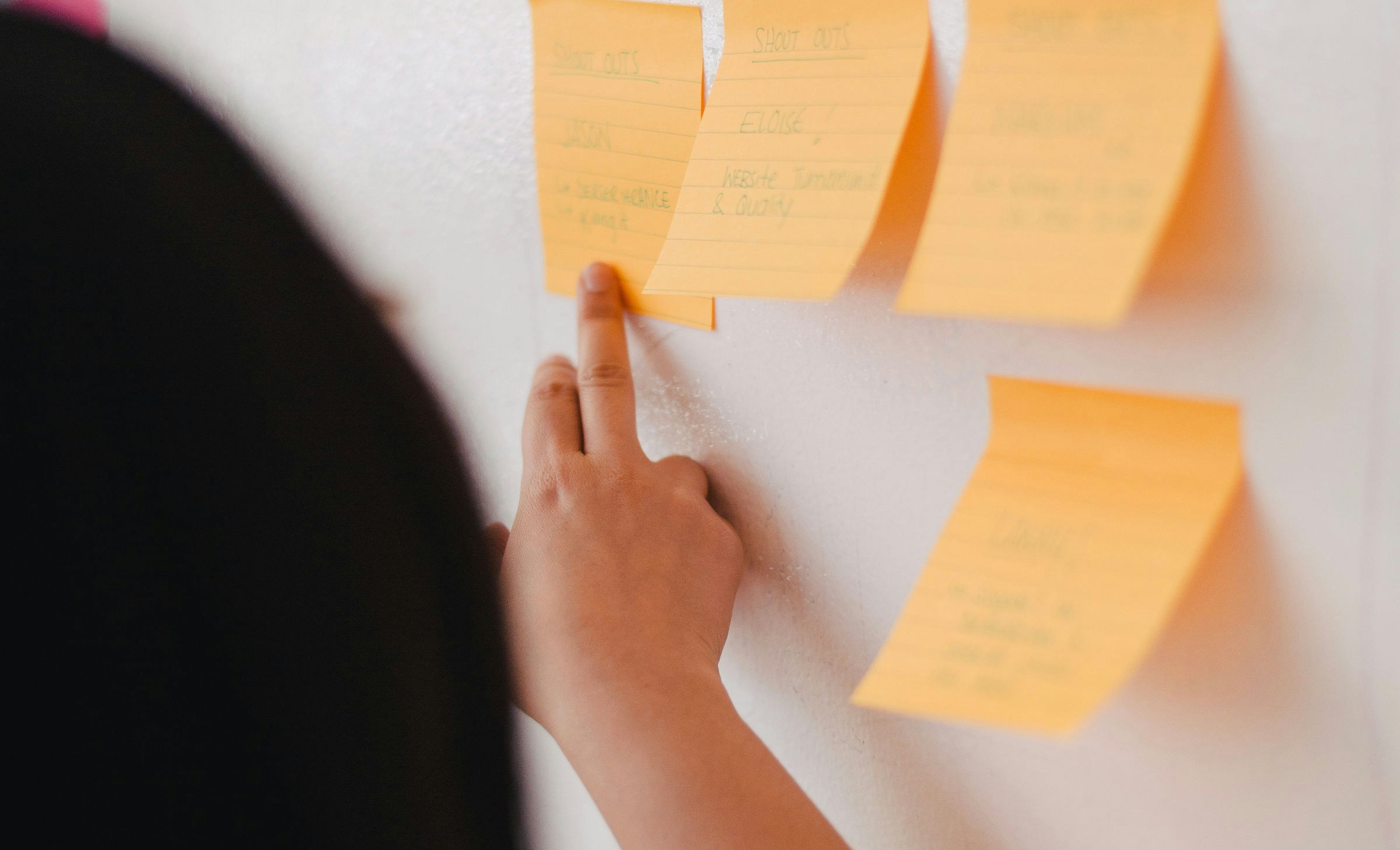 Person indicating post-its on a chalkboard